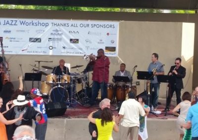 Photo of band playing on stage while people dance