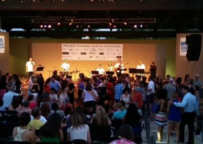 Photo of band playing on stage while people dance