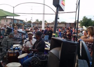 Photo of a drummer at a drum set, surrounded by people