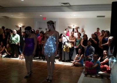 two women stand on dance floor while observers watch