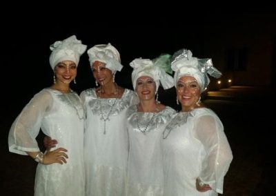 four people, dressed in all white, posing for a photo