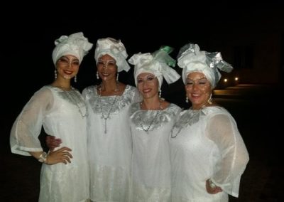 four people, dressed in all white, posing for a photo