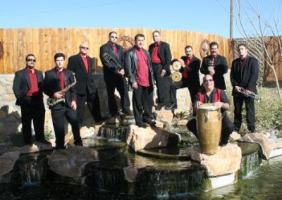 Photo of band with instruments standing behind of small body of water