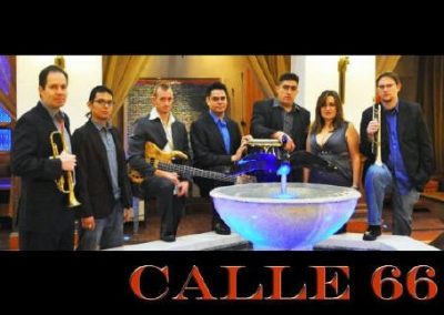 Photo of band, behind fountain, with instruments. Text at bottom reads"Calle66"