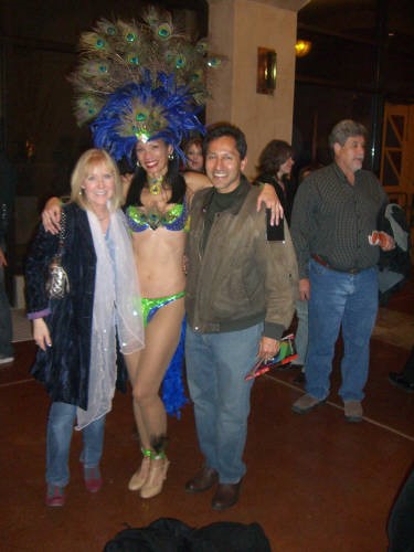 three people posing for a photo. one has a peacock hat